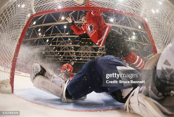 Brendan Gaunce of Team Canada flies over goaltender Joonas Korpisalo of Team Finland during the 2013 USA Hockey Junior Evaluation Camp at the Lake...