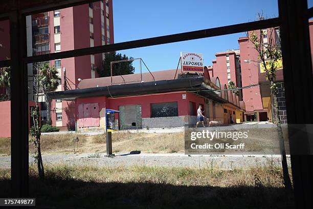 Man walks a dog past a derelict restaurant near the border between Spain and Gibraltar on August 7, 2013 in La Linea de la Concepcion, Spain....