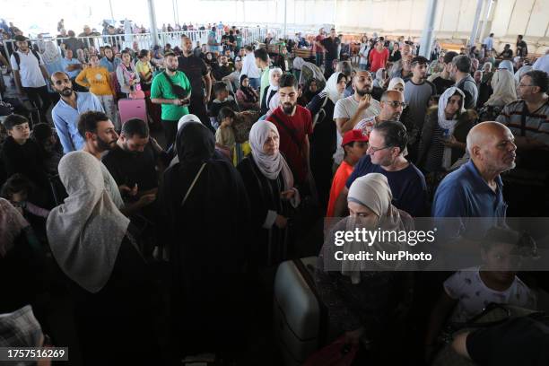 People sit in the waiting area at the Rafah border crossing in the southern Gaza Strip before crossing into Egypt on November 1, 2023. Scores of...