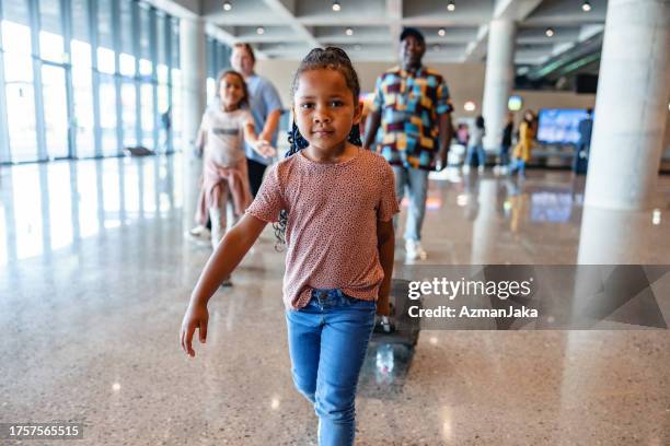 beautiful little girl leading her family to the exit of the airport - sliding door exit stock pictures, royalty-free photos & images