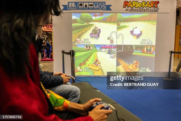 Visitors play "Mario Kart: Double Dash!!" video-game developped by Nintendo in 2003 for the GameCube during the "Paris Games Week" video-game fair in...