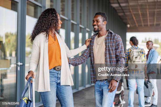 multicultural mid-adult couple saying goodbye at airport departure door - sliding door exit stock pictures, royalty-free photos & images