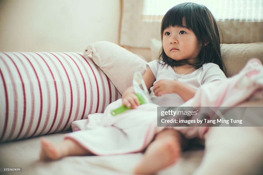 Toddler girl leaning on pillow sitting on the bed