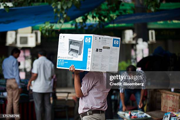 Man carries a boxed Hewlett-Packard Co. LaserJet printer in Nehru Place IT Market, a hub for the sale of electronic goods and computer accessories,...