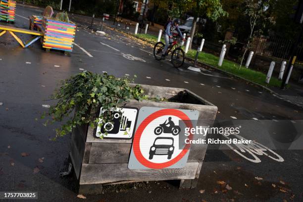 Cyclist passes planter barriers that form an LTN , a road closure feature by Southwark Council preventing motorists from accessing the junction of...