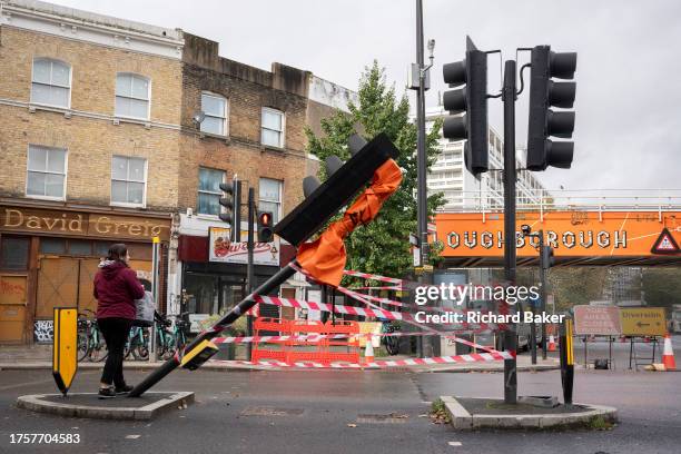 Pedestrian walks across a closed crossing in the aftermath of a collision with a traffic light post at Loughborough Junction, on 1st November 2023,...