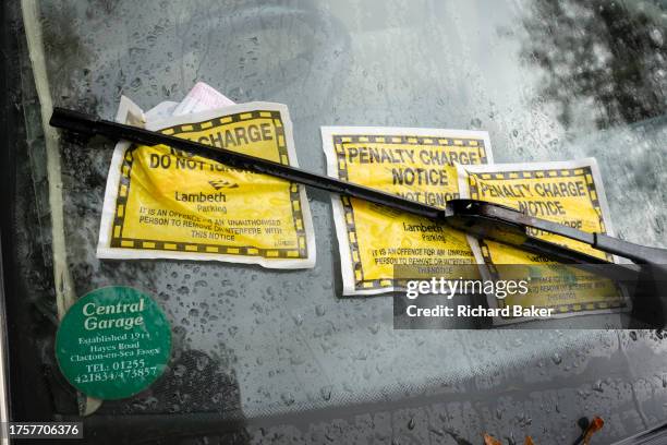 Three Fixed Penalty Charge Notices are pinned by the wipers on a car's windscreen in south London, on 1st November 2023, in London, England.