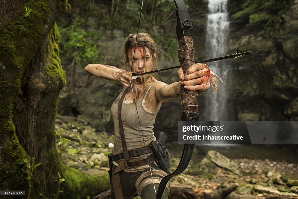 Hembra la heroína en la selva caza con arco y flecha