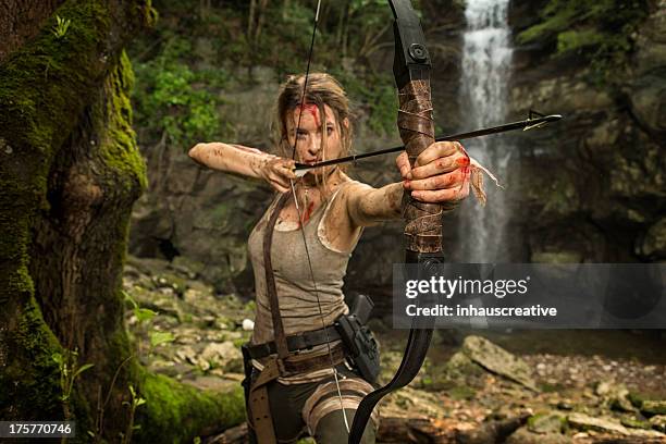 female heroine in the jungle hunting with bow and arrow - boog pijl en boog stockfoto's en -beelden