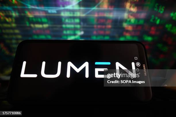 In this photo illustration, a Lumen logo is displayed on a smartphone with stock market percentages in the background.