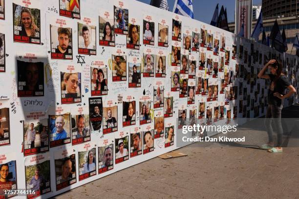 Member of the public looks at a wall displaying pictures of people still held hostage in Gaza, on October 26, 2023 in Tel Aviv, Israel. In the wake...