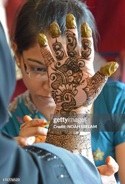 Stylist applies mehendi on the hands of a customer during 'Chand Raat' or 'Night of the Moon' in Hyderabad on August 8 traditionally held on the eve...