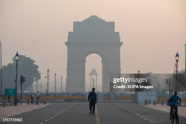 Man seen walking near Kartavyapath at India Gate, shrouded in the early morning smoggy haza. Air pollution in Delhi is primarily due to vehicles,...