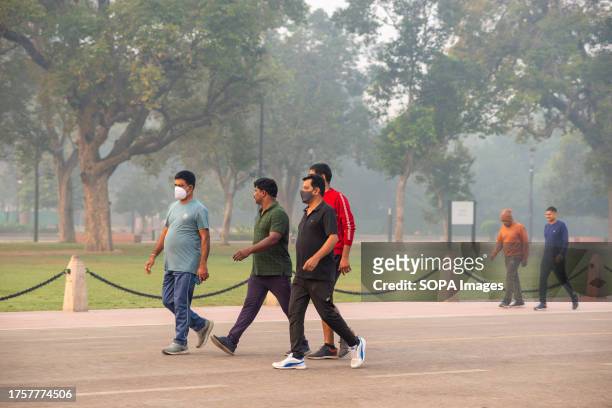Morning walkers seen wearing masks along Kartavyapath at India Gate, smog shrouded in the early morning haza. Air pollution in Delhi is primarily due...