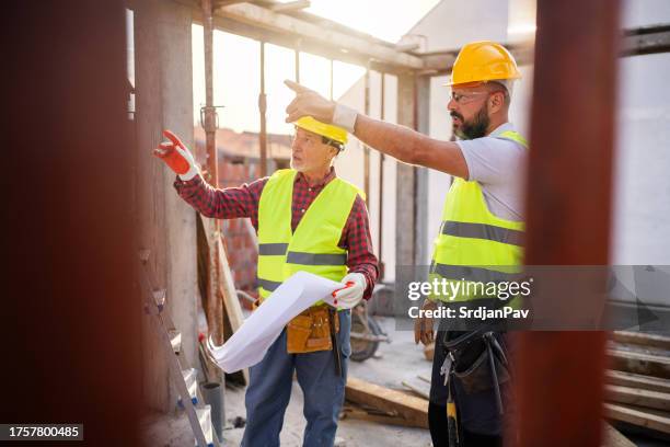 caucasian architect and building contractor having an meeting about project on a construction site - real estate developer stock pictures, royalty-free photos & images