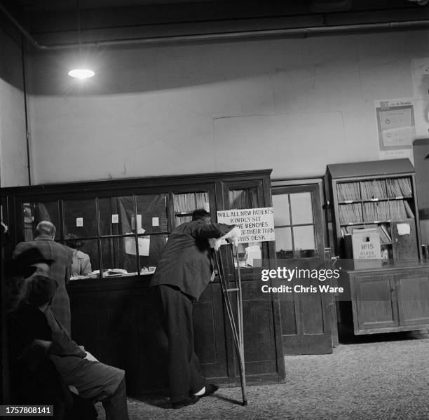 An outpatient leans on their crutch as they make an enquiry at the office of the Main Outpatients Hall of Guy's Hospital in Southwark, London,...