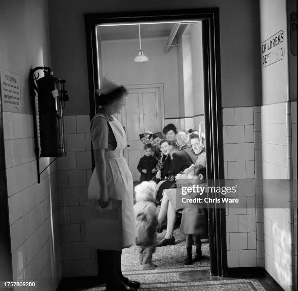 Nurse stands in a doorway as a group of children sit waiting to be seen at Guy's Hospital in Southwark, London, England, February 1948.