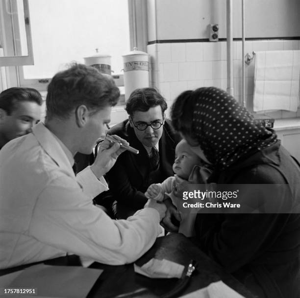 Doctor uses a pen torch to examine a baby in the children's clinic at Guy's Hospital in Southwark, London, England, February 1948.