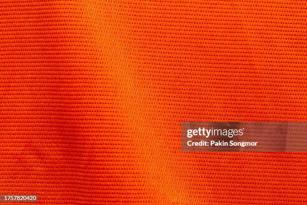 orange color sports clothing fabric football shirt jersey texture and textile background. - pro to pro textile stock pictures, royalty-free photos & images