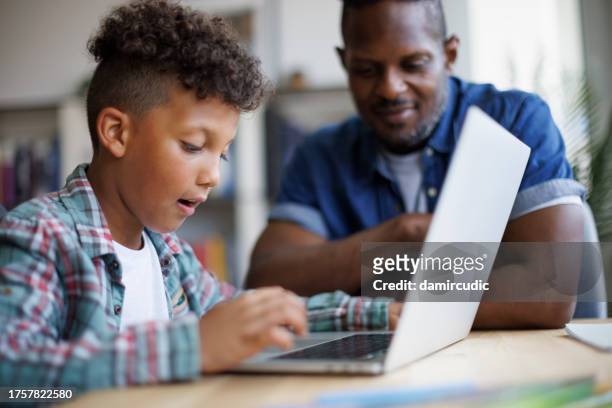 father and son using laptop at home - dad homework stock pictures, royalty-free photos & images