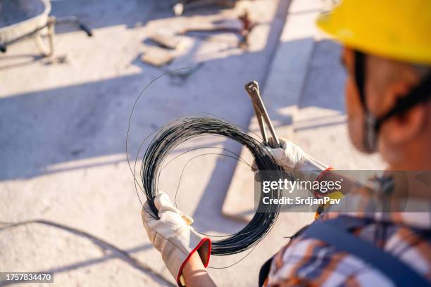 over the shoulder view of construction worker, working on a constructions site - pliers stockfoto's en -beelden