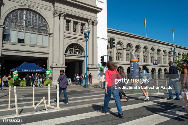 People walk on the Embarcadero on a sunny day in front of the Ferry Building in downtown San Francisco, California, August 17, 2023.