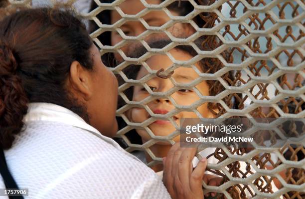 Ana Gomez and a family member in Mexico kiss through the U.S./Mexico border fence at Border State Park February 1, 2003 west of San Ysidro,...