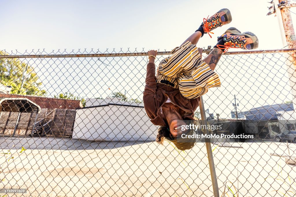 Young woman smiling and hanging upside down on fence