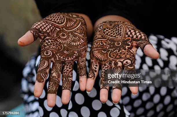 Girl showing her hands decorated with henna ahead of Eid-ul-Fitr on August 8, 2013 in Noida, India. Markets across the Muslim world witness huge...