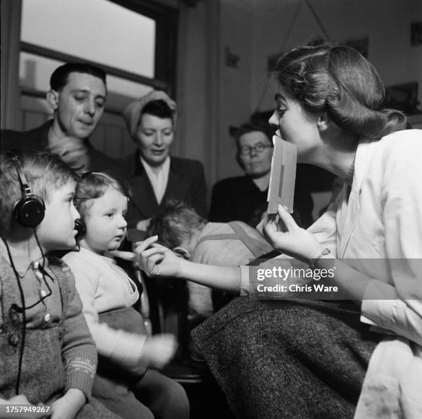 Assistant speech therapist Miss Sowerby places a finger under a hearing impaired child's chin during a group lesson at a London clinic in January...