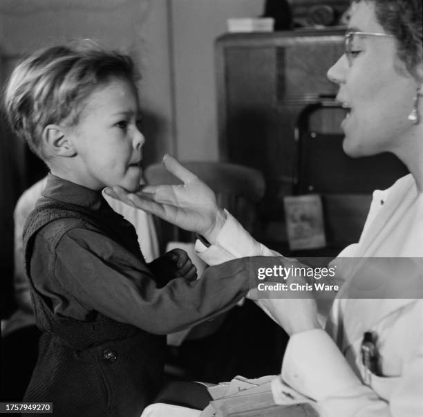 Speech therapist Sylvia Martin touching the chin of a hearing impaired boy named Paul Phillips, aged three, during a lesson at a London clinic in...