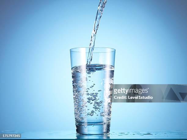 cold drink water being poured into glass - fülle stock-fotos und bilder