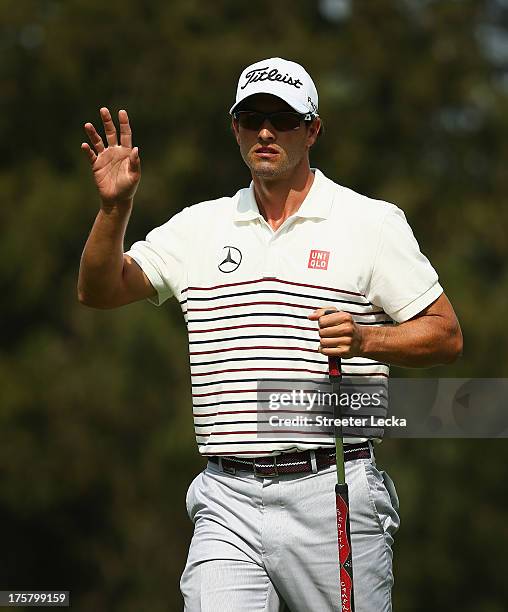 Adam Scott of Australia waves after making a putt for birdie on the eighth hole during the first round of the 95th PGA Championship on August 8, 2013...