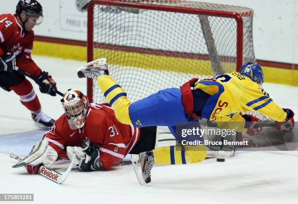 Zachary Fucale of Team Canada makes the pad save on Gustav Possler of Team Sweden during the 2013 USA Hockey Junior Evaluation Camp at the Lake...