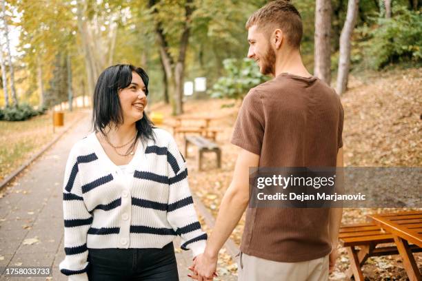 millennial generation couple spending time outside in autumn holding hands - cute girlfriends stock pictures, royalty-free photos & images