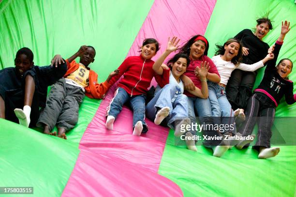 Multi-ethnic group of cheerful children is playing and laughing on a bouncy slide on July 3, 2004 in Sarcelles, a Paris suburb, France