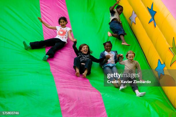 Multi-ethnic group of cheerful children is playing and laughing on a bouncy slide on July 3, 2004 in Sarcelles, a Paris suburb, France