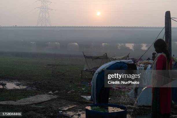 Woman washes her face with water in a field amidst smog in New Delhi, India on November 1, 2023.