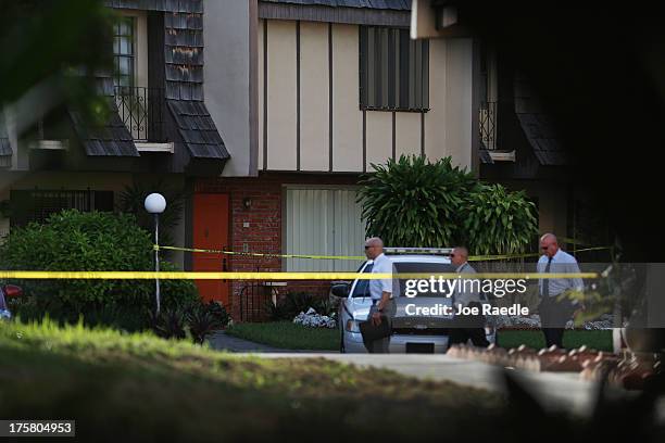 Police detectives walk past the orange door which is the front door to a townhouse where seemingly a husband reportedly confessed on Facebook to...