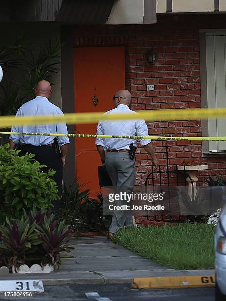 Police detectives walk past the orange door which is the front door to a townhouse where seemingly a husband reportedly confessed on Facebook to...
