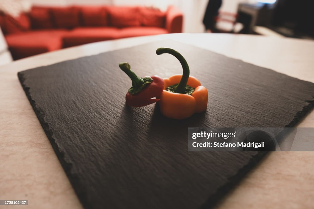 Colored sweet peppers on black slate board, close range