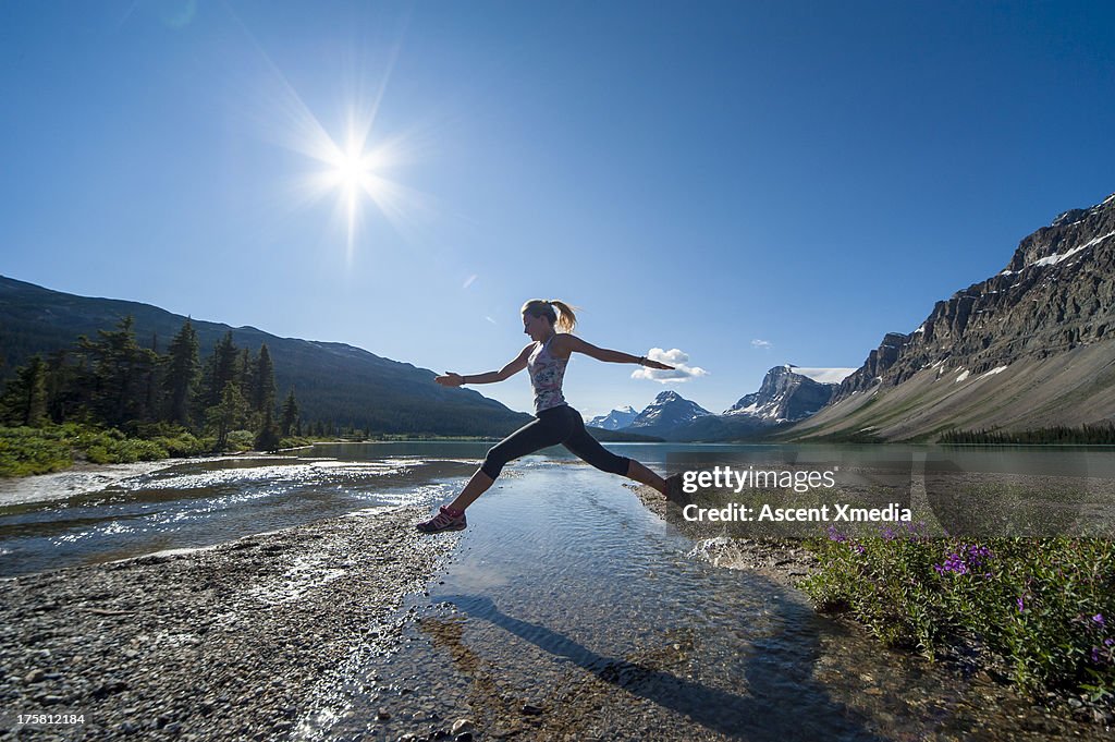 Teenage runner jumps across creek, mountain lake