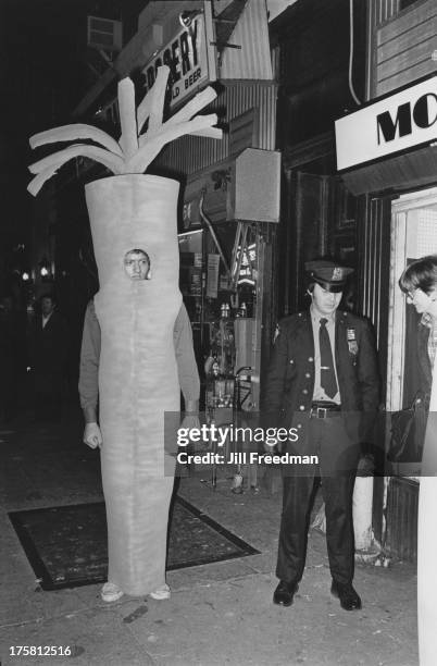 An officer of the NYPD stands next to a man in a carrot costume on Hallowe'en in New York City, circa 1979.