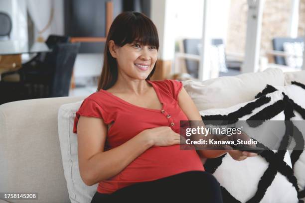 indonesian pregnant mom binge watching her tv series at home - binge tv stockfoto's en -beelden
