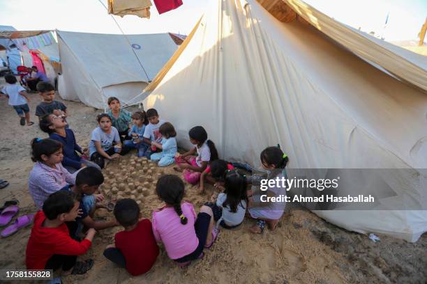 Group of children make sand castles beside tents at a refugee camp set up for Palestinians seeking refuge along the Gaza Strip on October 26, 2023 in...