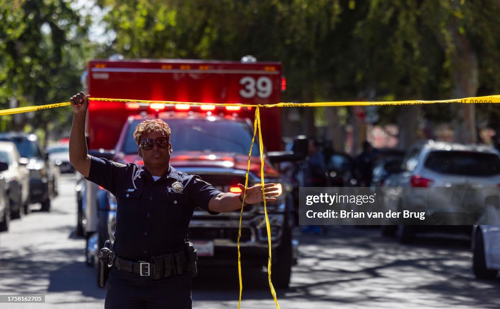 Police officer lifts police tape to let an ambulance leave