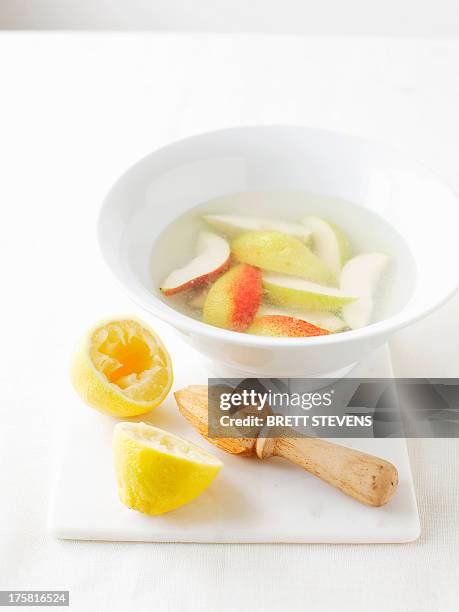 bowl of water with lemon juice to prevent vegetables from browning - zitronensaft stock-fotos und bilder