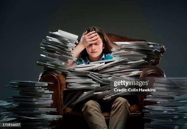 girl sitting in leather armchair with piles of books - gestapelt leder stock-fotos und bilder