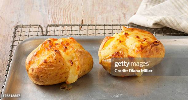 baked potatoes with cheese on metal baking sheet - jacket potato stock pictures, royalty-free photos & images