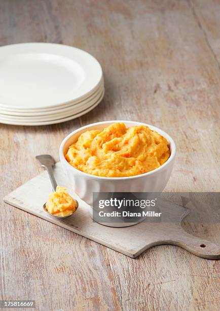 carrot, swede and potato mash in rustic white bowl with large metal spoon - kohlrübe stock-fotos und bilder